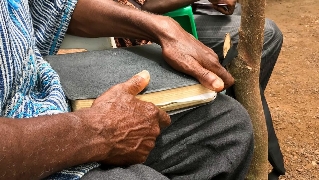 Man holding a Bible in a West African village
